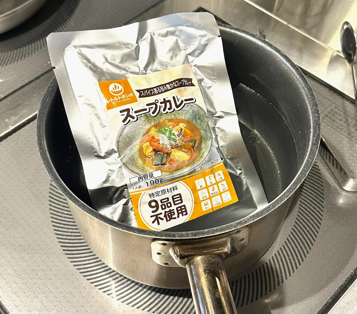 鍋で湯せんしているレトルトホンポのパウチ(スープカレー)