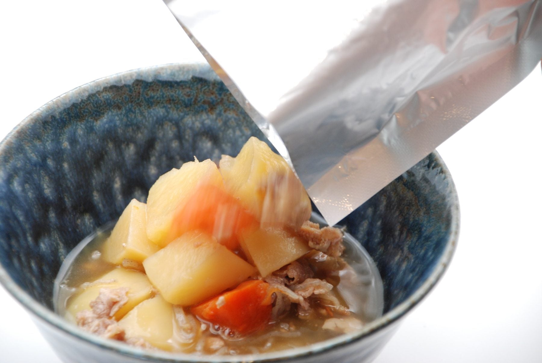 レトルトパウチから器に肉じゃがを盛りつけているところ